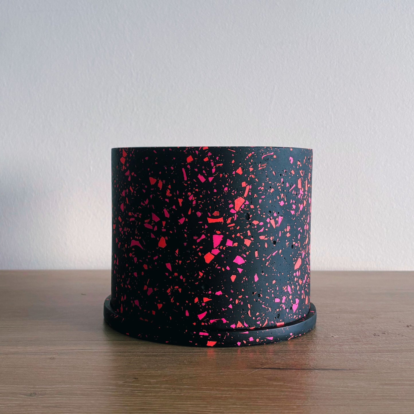 Black container with pink speckles on a wooden surface