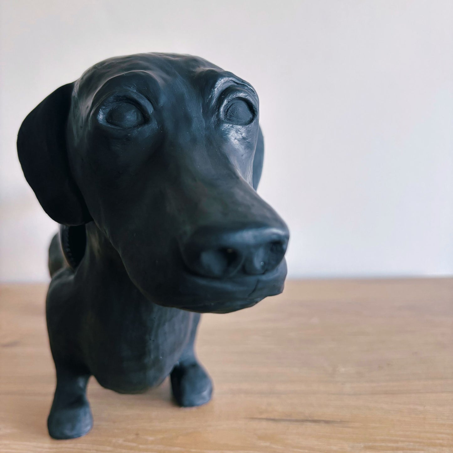 Black dog-shaped object on a wooden surface with a white background