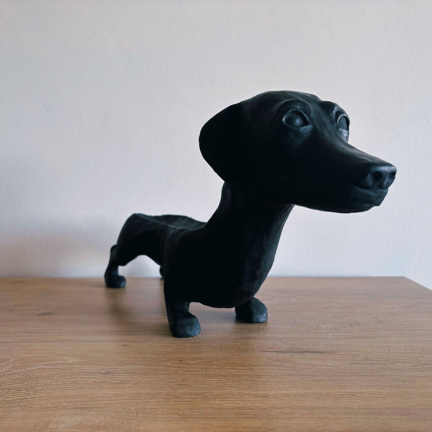 Black dog figurine on a wooden surface with a plain background