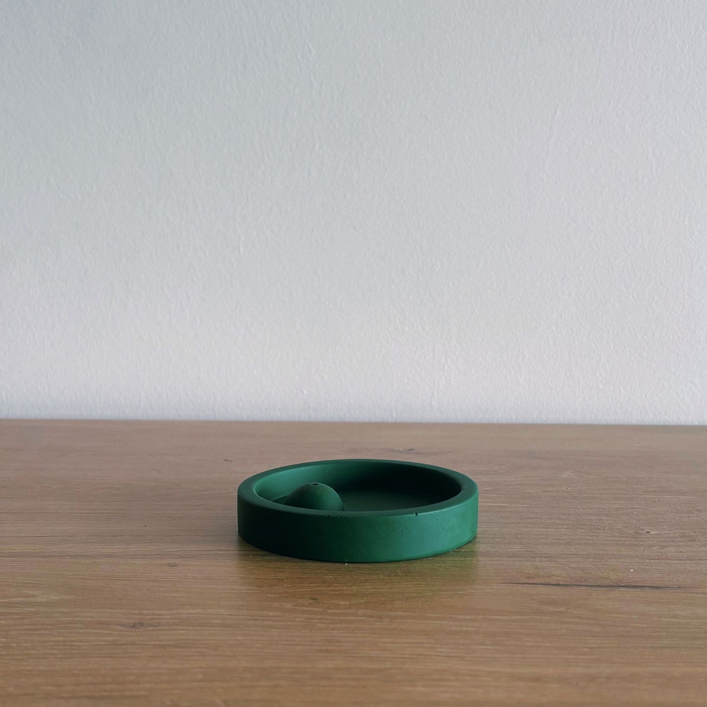 Green ceramic incense burner on a wooden surface with a white background