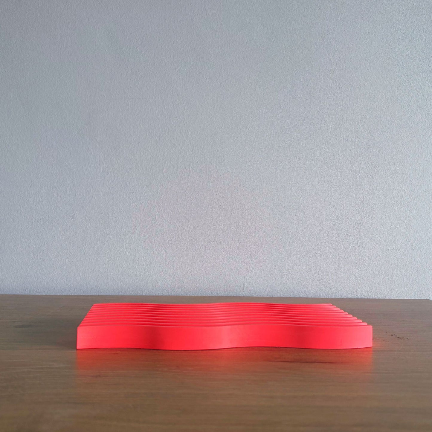 red rectangular object on a wooden surface with a light gray background