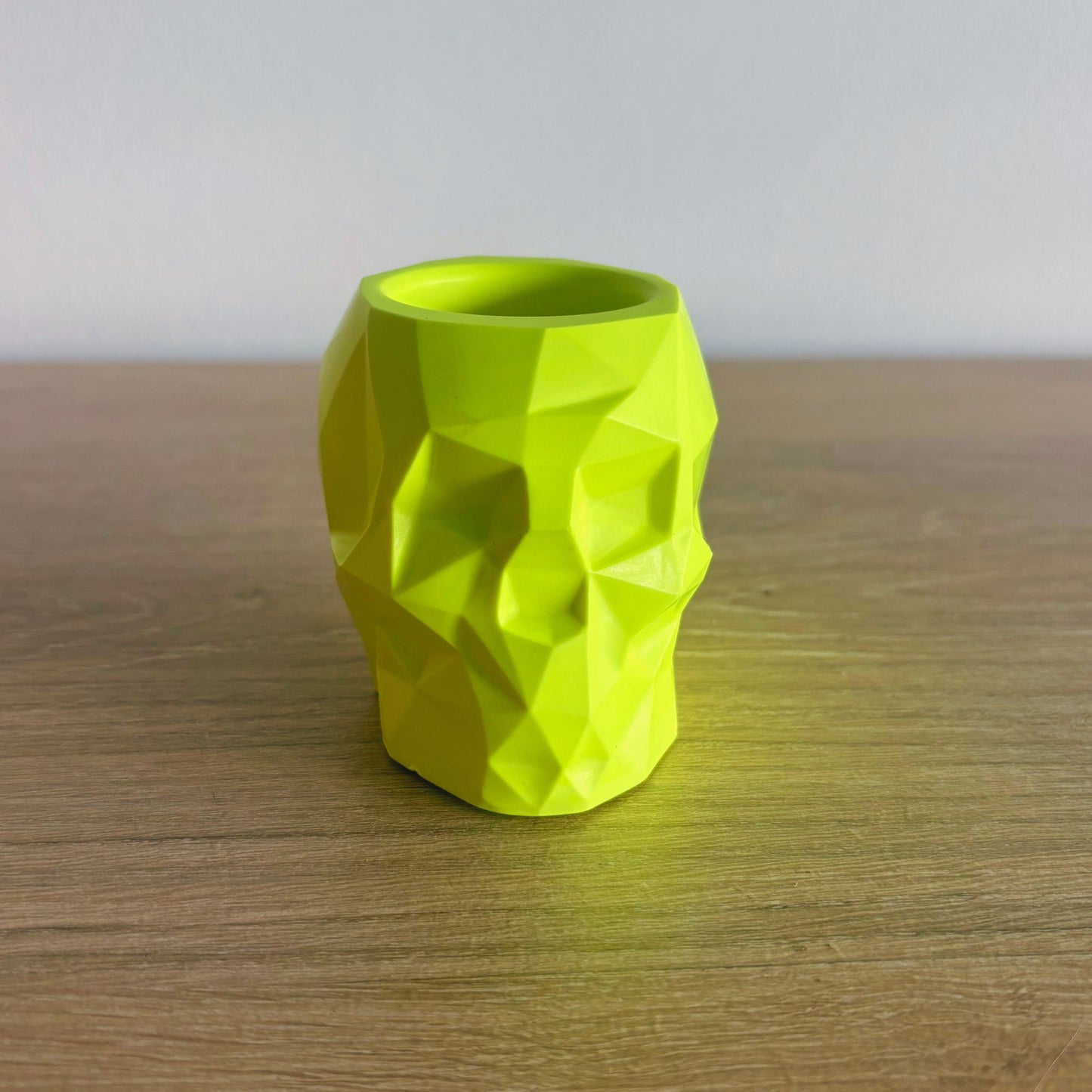 Green geometric-patterned vase on a wooden surface with a neutral background