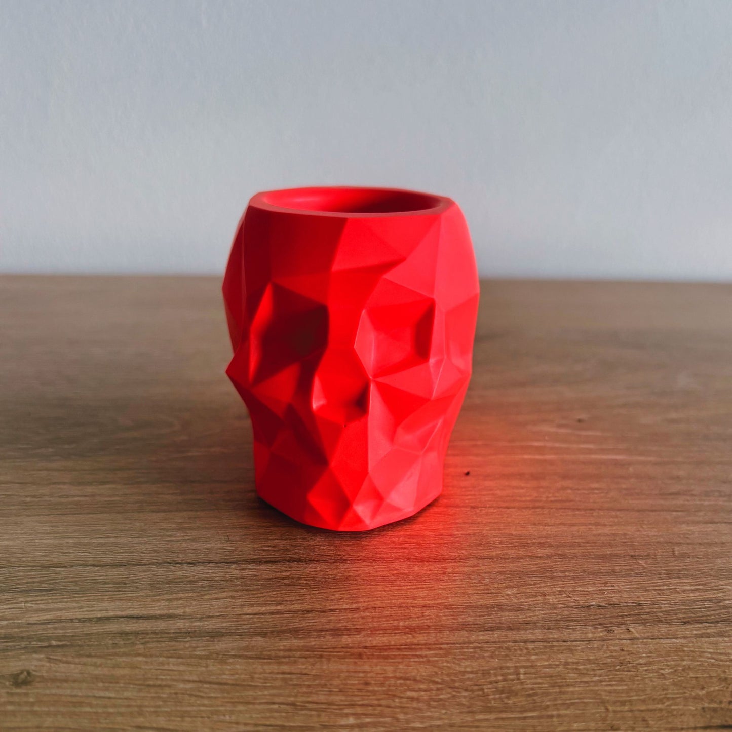 Red geometric-patterned vase on a wooden surface with a neutral background