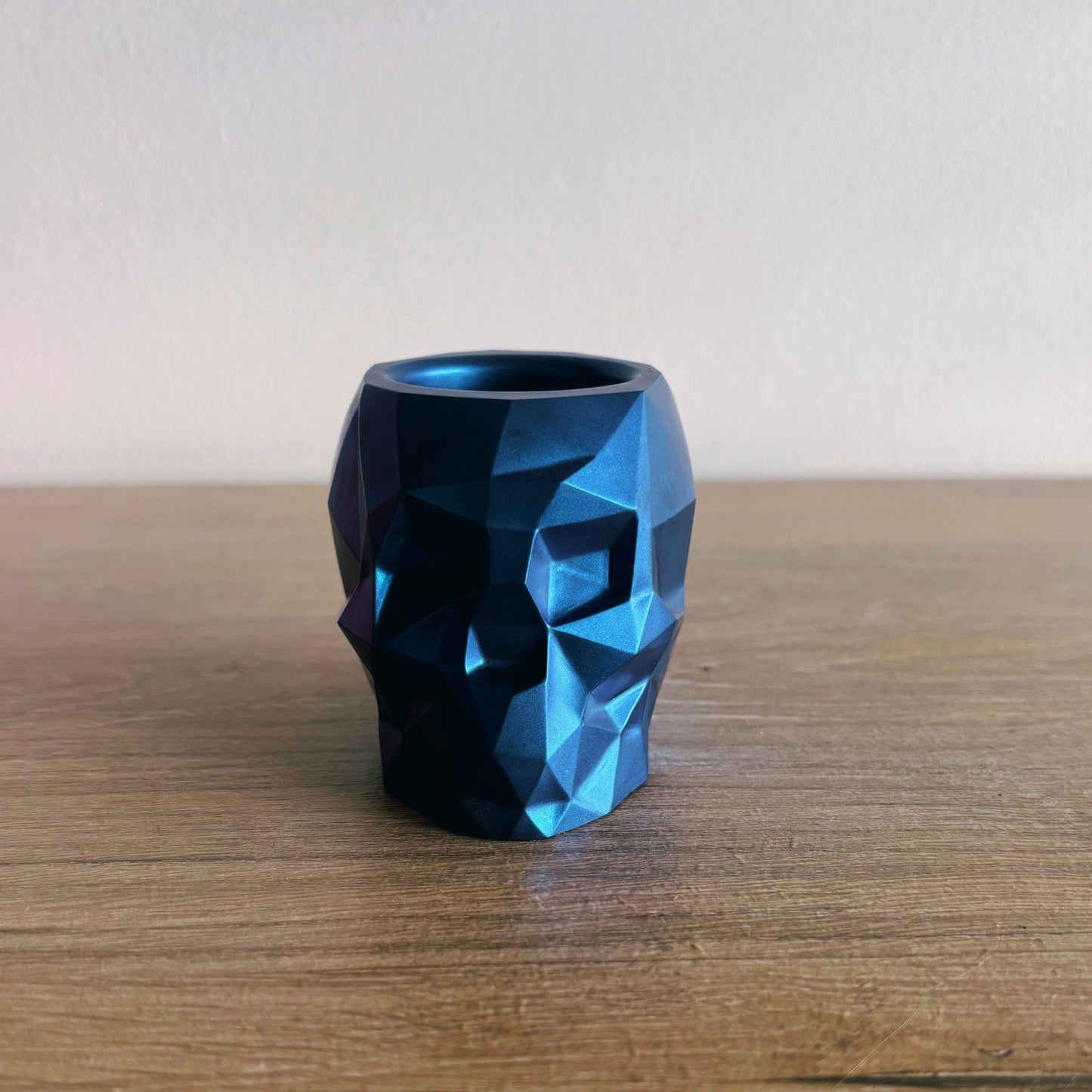 Blue geometric-patterned vase on a wooden surface with a plain background