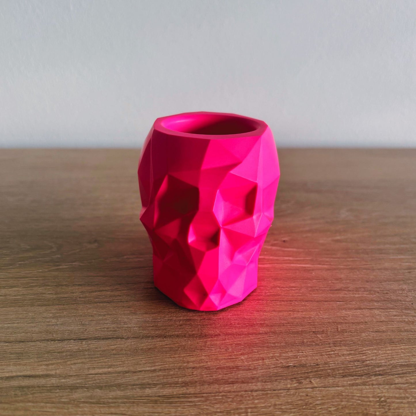 Pink geometric-patterned vase on a wooden surface with a plain background