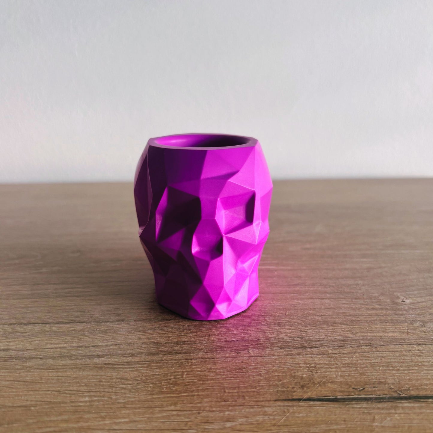 Purple geometric-patterned vase on a wooden surface with a plain background