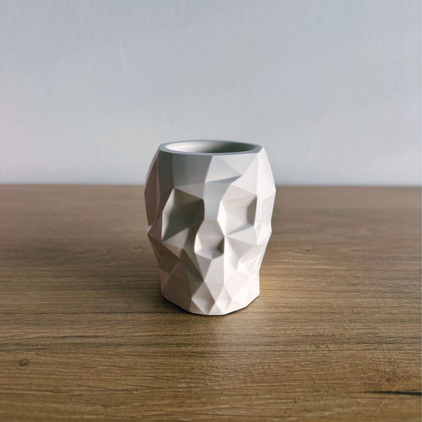 Geometric ceramic skull pot on a wooden surface with a plain background