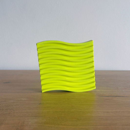 Yellow textured square object on a wooden surface with a white background