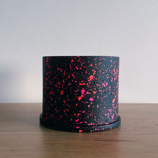Black container with pink speckles on a wooden surface