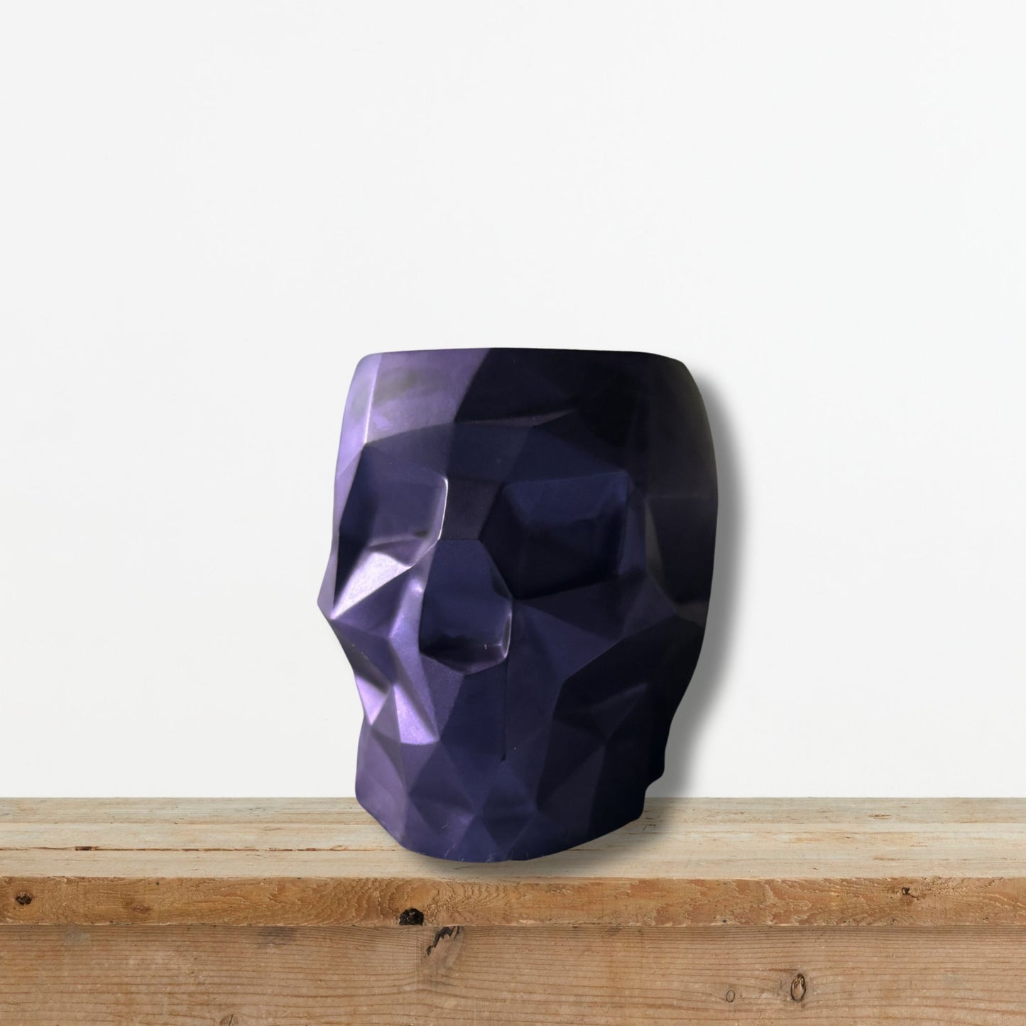 Faceted purple skull on a wooden surface with a white background