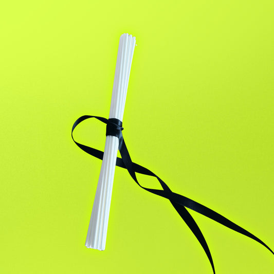 white diffuser reeds with black ribbon on a bright green background