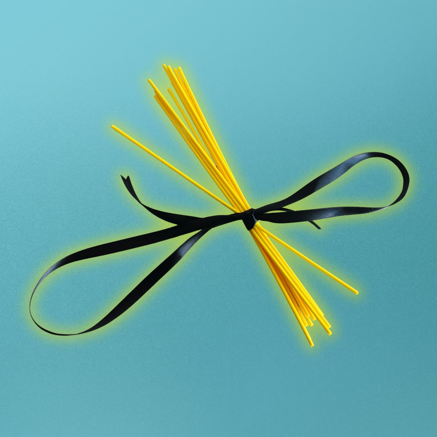 Yellow diffuser reeds tied with a black ribbon on a blue background