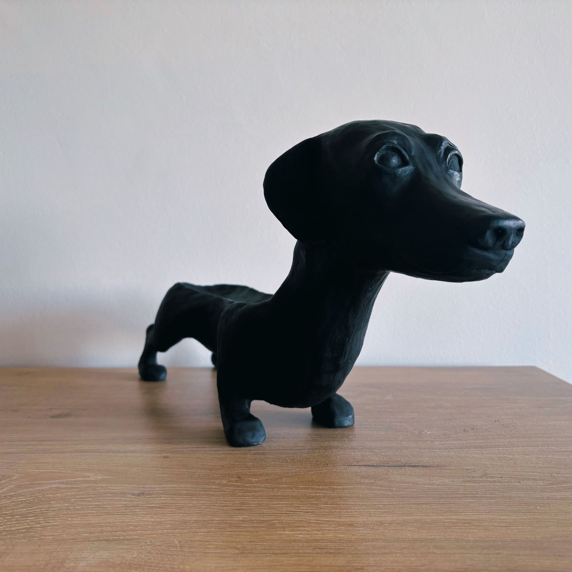 Black dog figurine on a wooden surface with a plain background
