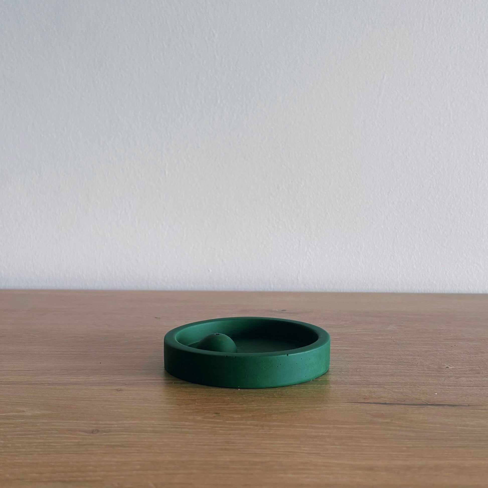 Green ceramic incense burner on a wooden surface with a white background