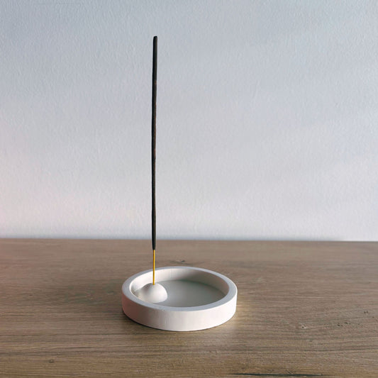 Incense holder with a single incense stick on a wooden surface