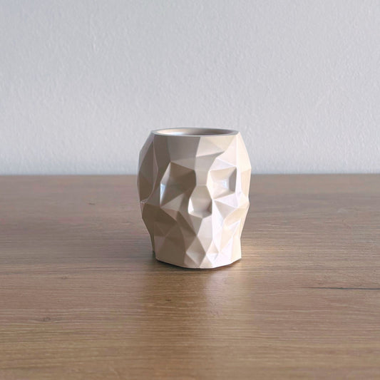 Geometric face-shaped vase on a wooden surface with a plain background