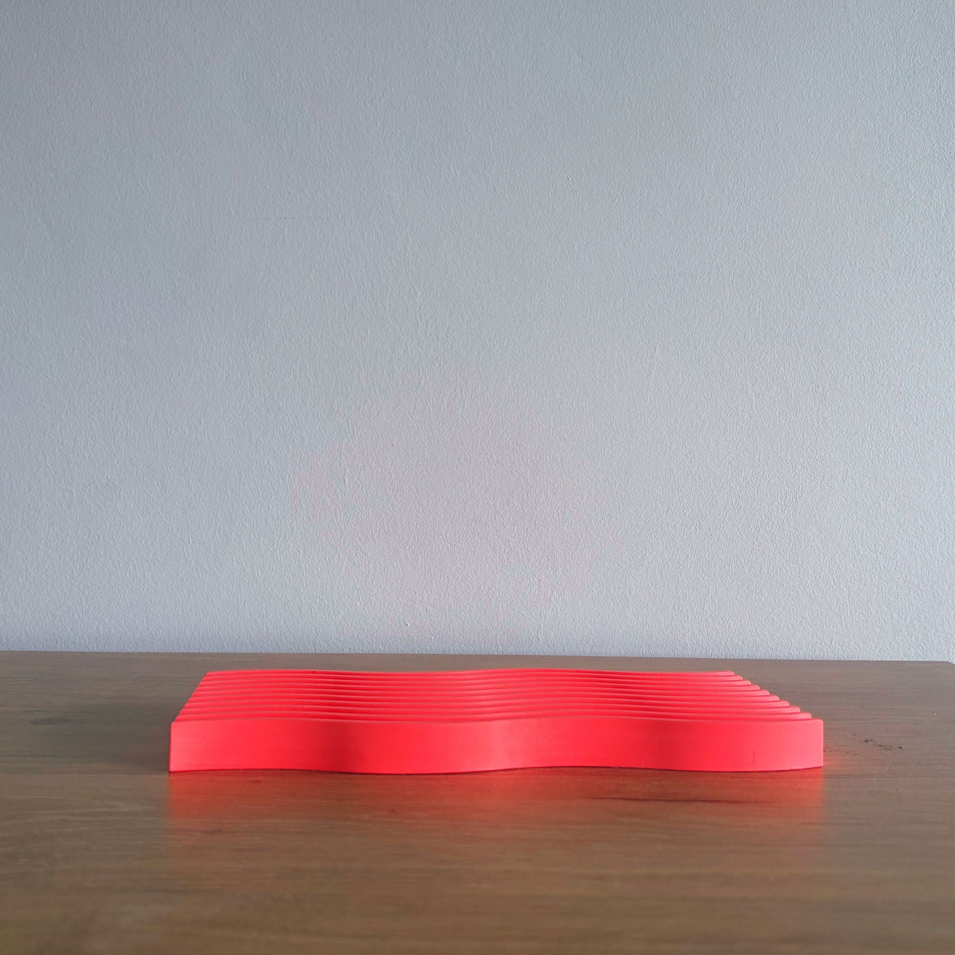 red rectangular object on a wooden surface with a light gray background