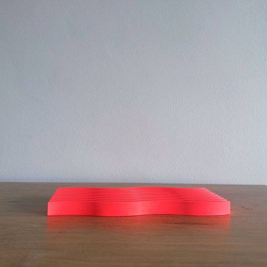 red rectangular object on a wooden surface with a light gray background