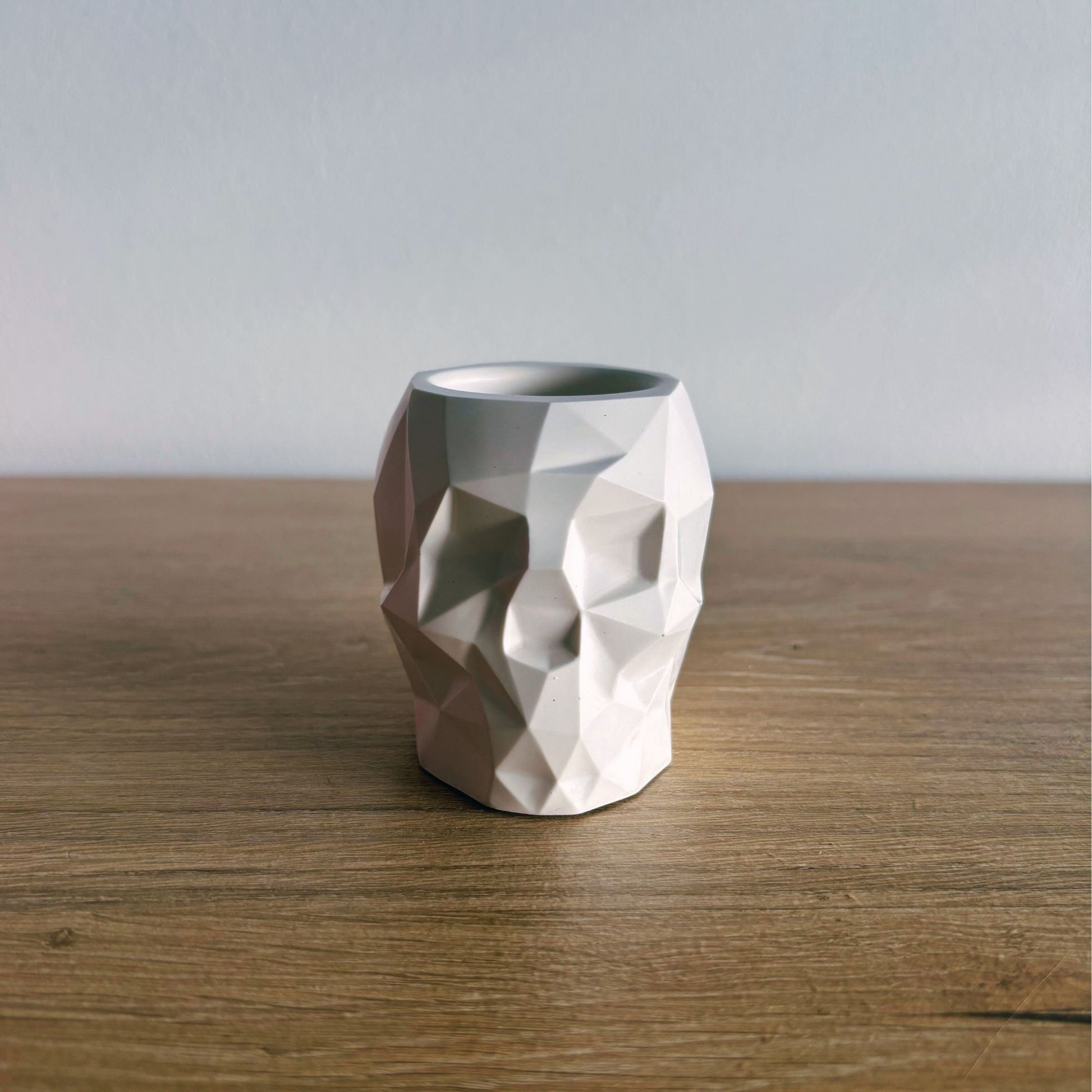 Geometric ceramic skull pot on a wooden surface with a plain background